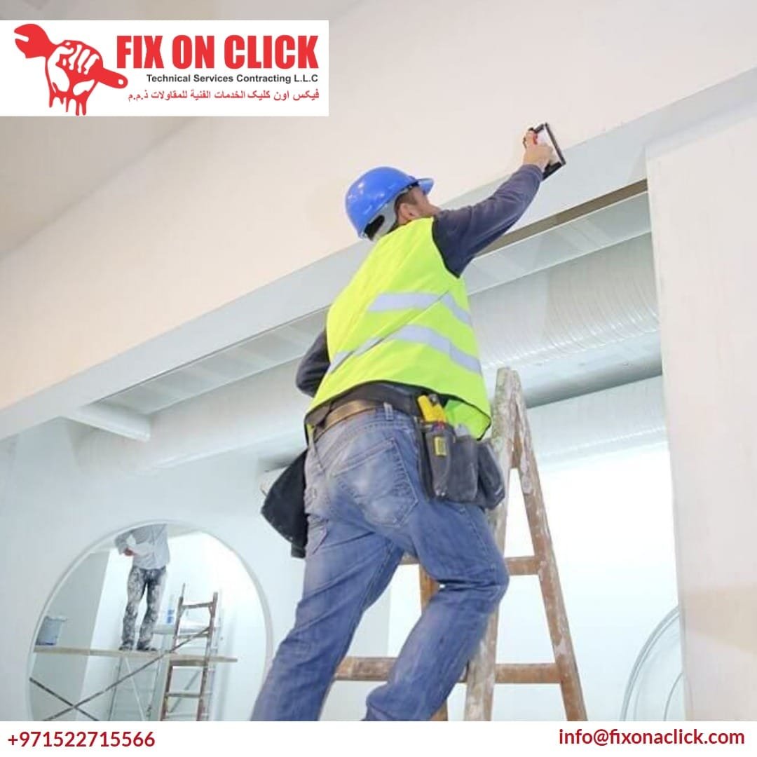 Technician inspecting a gypsum ceiling for cracks and water damage in Dubai